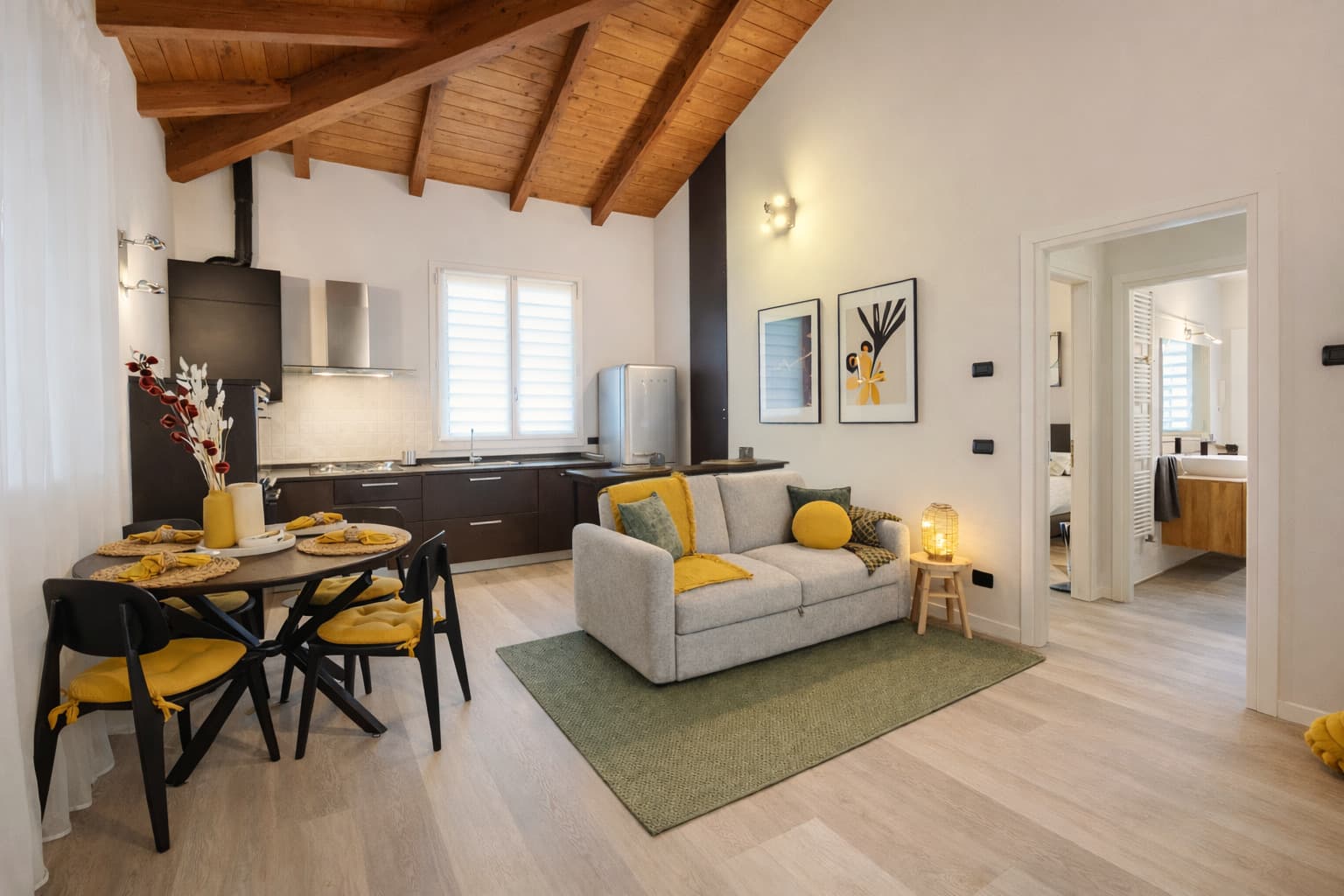 Zona giorno luminosa con cucina e soffitto in legno